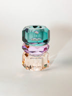 Ein hoher wendbarer Dioptrics Kerzenhalter aus Glas in Petrol, Violett und Pfirsich Kristall-Optik, bestehend aus mehreren geometrischen Flächen. Der Kerzenhalter hat eine moderne, facettierte Optik, die das Licht reflektiert, umgedreht