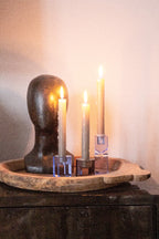 Der Kristallhalter auf einem Bestelltisch mit Angezündeten Stabkerzen darin und einem Dekokopf