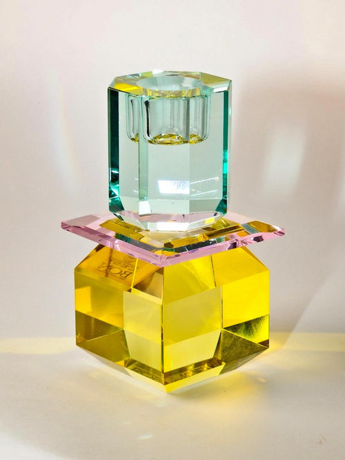 Ein hoher Dioptrics Kerzenhalter aus Glas in Hellgelb, Rosa, Hellminze Kristall-Optik, bestehend aus mehreren geometrischen Flächen. Der Kerzenhalter hat eine moderne, facettierte Optik, die das Licht reflektiert