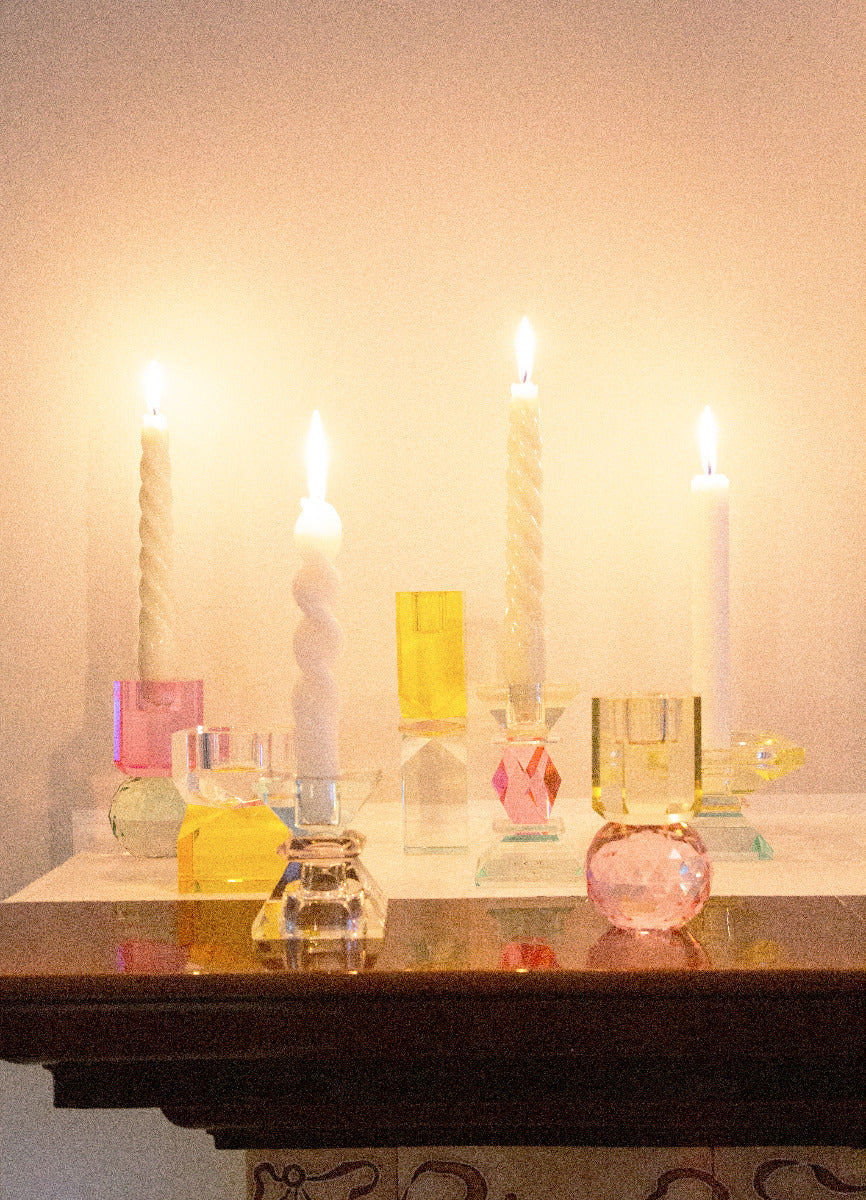 Verschiedene Kristallhalter auf einem Tisch mit Stabkerzen die angezündet sind