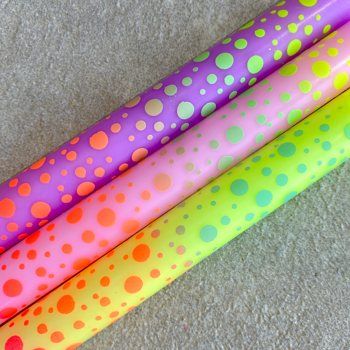 Drei Stabkerzen in regenbogen Farben mit Punkten, die ebenfalls in vielen Farben auf der Kerze sind, Nahaufnahme