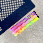 Drei Stabkerzen in regenbogen Farben mit Punkten, die ebenfalls in vielen Farben auf der Kerze sind, in der Sonne