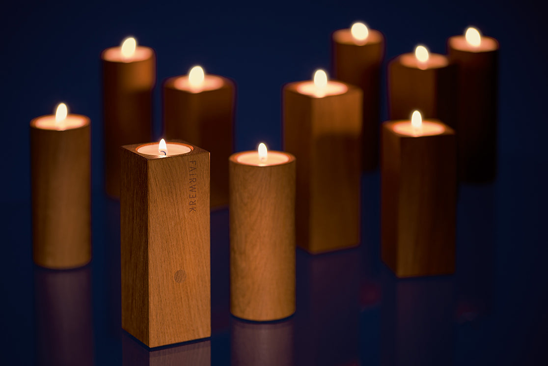 Eine große anzahl an Teelichthaltern aus Holz in der dunkelheit mit brennendem Teelicht