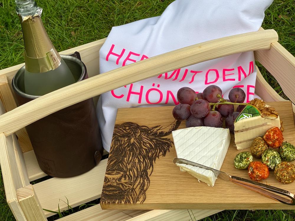 Das Baumwoll-Geschirrtuch hergerichtet in einem Korb mit Wein, Käse und Weintrauben