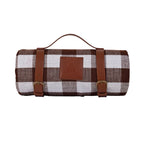 Wasserdichte Picknickdecke eingerollt mit Riemengurten in Lederoptik und Metallschnallen fixiert, Tragegriff um Picknickdecke zu transportieren, braunkarierte Picknickdecke