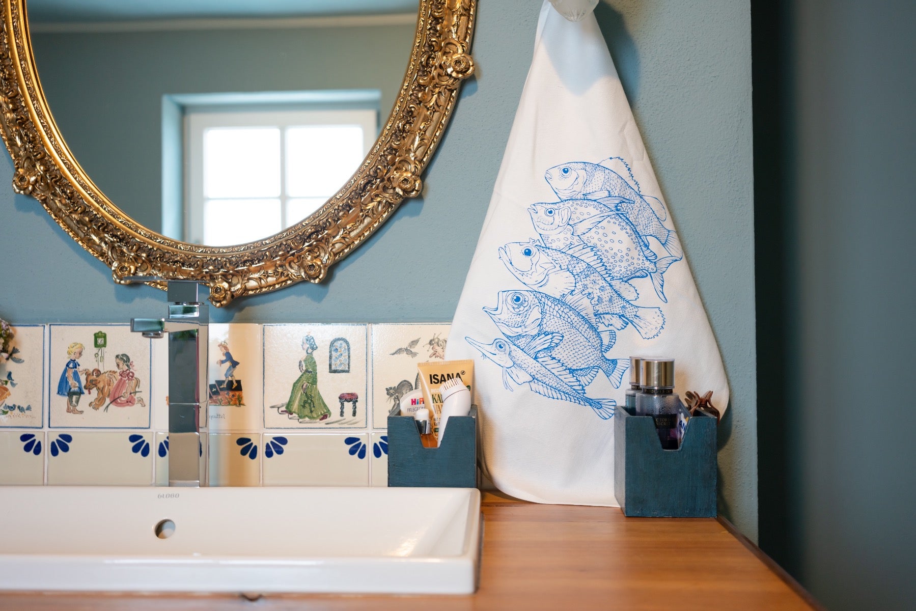 Weißes Geschirrtuch mit einem blauen Aufdruck von 5 Fischarten aufgehangen im Badezimmer