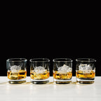 Vier Whisky-Gläser mit aufgedruckten "Hochlandrind" Design, auf einem Tisch in dem Whisky gefüllt ist