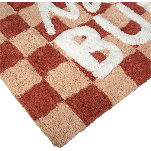 Rot Beige karierte Badematte mit der weißen Schrift "Nice Bum" Nahaufnahme einer Ecke