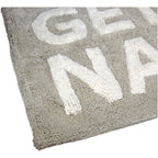 Taupe Badematte mit der weißen Schrift "Get Naked" Nahaufnahme einer Ecke