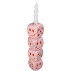 Pinker Kerzenständer aus gestapelten Würfeln auf denen Punkte und Smiley zu sehen sind. und eine Weiße befestigte Stabkerze