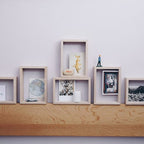 Viele Rahmen aus Eschenholz an einer Wand mit verschiedenen Postkarten und Objekten