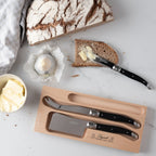 Die Käse-Messer in benutzung auf einem Tisch mit Butter, Brot und Käse