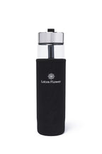 Die Trinkflasche in einer schwarzen Flaschenhusse auf der steht "Lotos Flower"