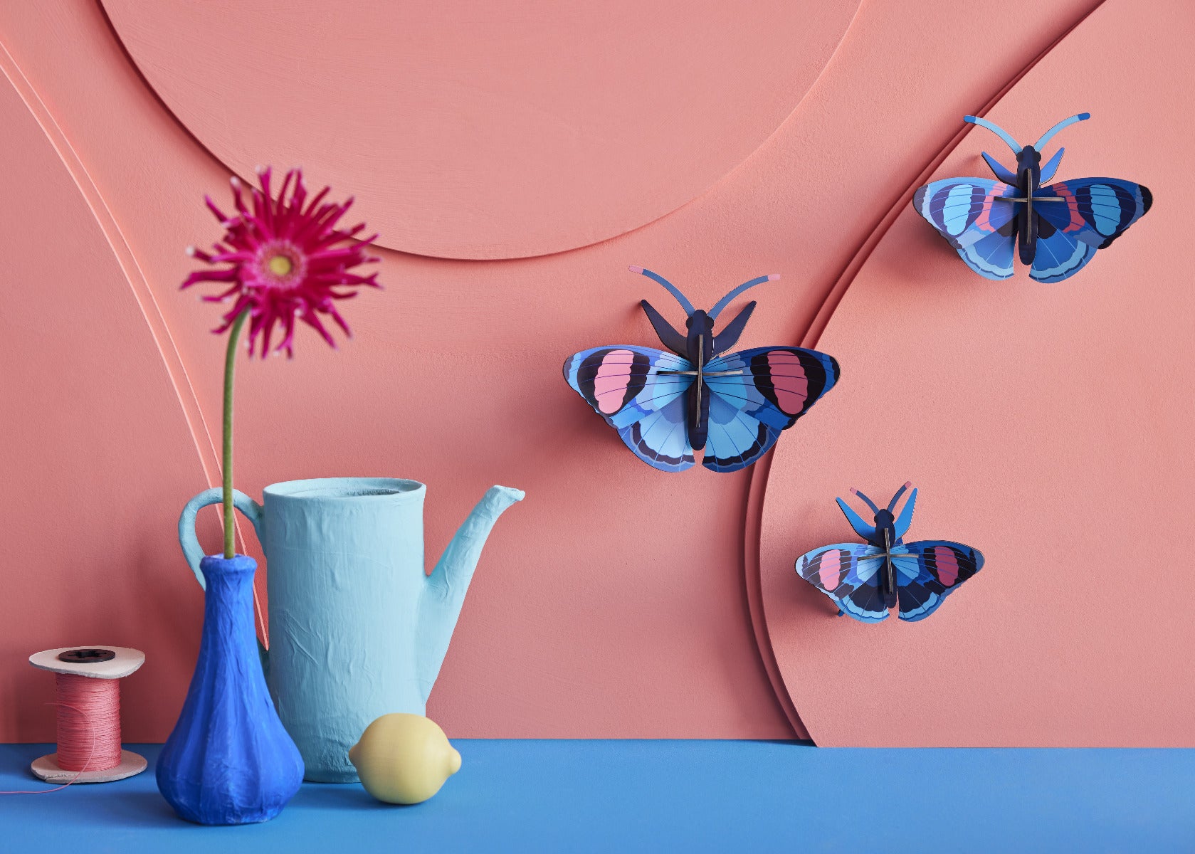 Drei Pfauenaugen 3D Wanddeko an der orangenen Wand befestigt