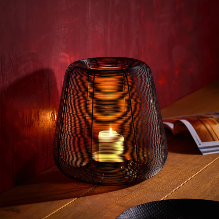 Großes Windlicht aus Mesh mit angezündeter Kerze darin, auf einem Tisch in einem stilvoll eingerichteten Raum