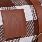 Closeup von Lederpatch auf der zusammengerollten Picknickdecke, patch mit eingestanztem Bienensymbol