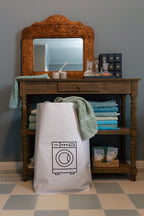 Tüte aus Kraftpapier mit einer aufgedruckten schwarzen Waschmaschine und einem braunen Rand, stehend in einem Badezimmer