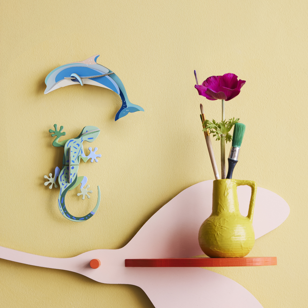 3D Delfin Wanddeko und grüner Gecko Wanddeko angerichtet auf gelber Wand zusammen mit dekorativer Vase 