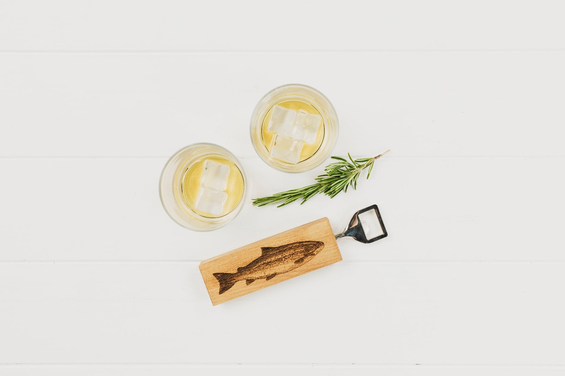 Ein Flaschenöffner mit einem rechteckigen Eichenholzgriff, auf dem ein Fisch-Motiv eingebrannt ist