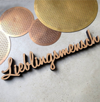 Holzschriftzug Wanddekoration in der schwarzen Schrift "Lieblingsmensch" auf einem Tisch