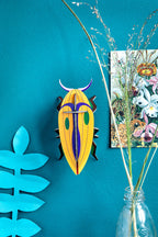 Die Gelbe Käfer Wanddekoration an einer blauen Wand befestigt umgeben von anderen Dekorationsobjekten