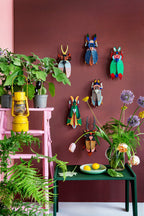 3D Wanddekoration eines farbigen Grashoppers zusammen mit anderen Käfern an einer Wand