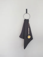 Der Handtuchhalter in Ring Form an der Wand befestigt mit einem schwarzen Lederriemen in dessen Ring ein Handtuch hängt
