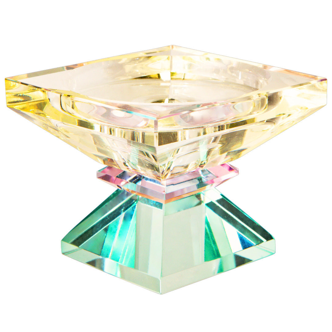 Ein hoher Dioptrics Kerzenhalter aus Glas in Hellgelb, Pink und Hellminze Kristall-Optik, bestehend aus mehreren geometrischen Flächen. Der Kerzenhalter hat eine moderne, facettierte Optik, die das Licht reflektiert