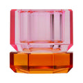 Ein kleiner Dioptrics Kerzenhalter aus Glas in Pink und Bernstein Kristall-Optik, bestehend aus mehreren geometrischen Flächen. Der Kerzenhalter hat eine moderne, facettierte Optik, die das Licht reflektiert