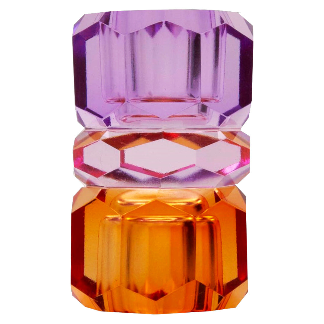 Ein hoher wendbarer Kerzenhalter aus Glas in Violett, Pink und Bernstein Kristall-Optik, bestehend aus mehreren geometrischen Flächen. Der Kerzenhalter hat eine moderne, facettierte Optik, die das Licht reflektiert