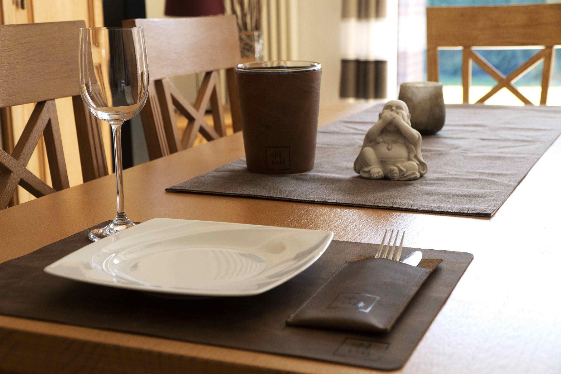 Der Besteckumschlag auf einem gedeckten Tisch mit der Leder-Kerze im Hintergrund