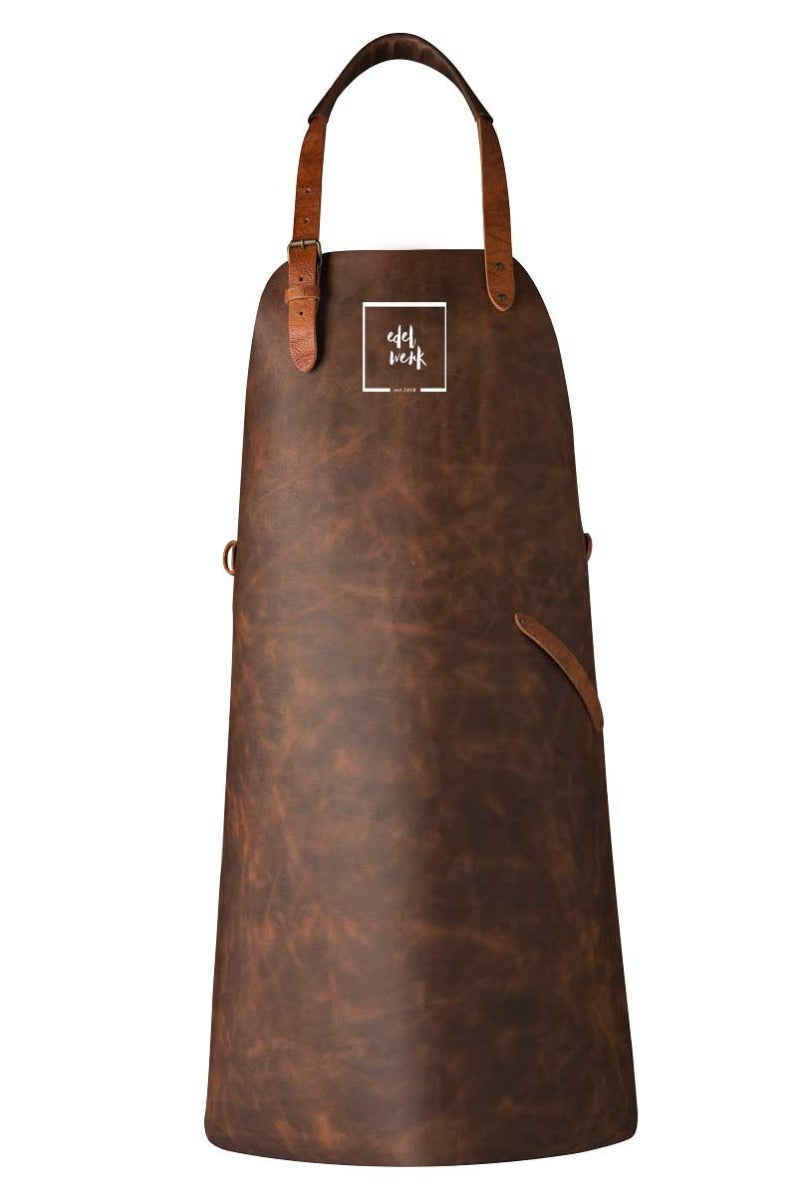 Leder-Schürze in Cognac Farbe mit braunen verstellbaren Lederriemen zum tragen, an der Brust ist das Edel Werk Logo in Weiß gedruckt