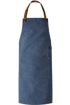 Eine blaue Canvas-Schürze mit Träger aus braunem Leder.