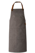 Eine graue Canvas Schürze mit Träger aus braunem Leder.
