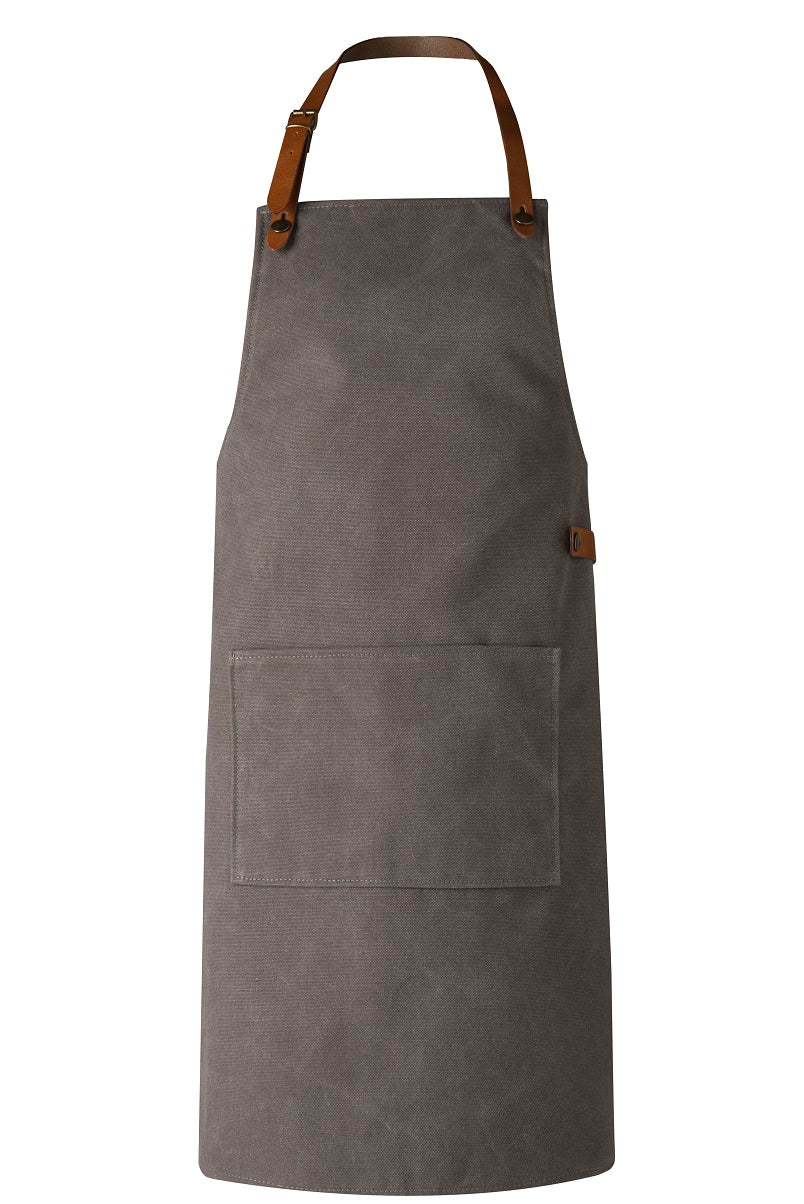 Eine graue Canvas Schürze mit Träger aus braunem Leder.