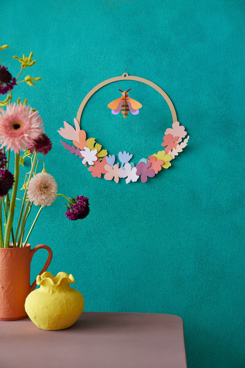 Wanddekoration Wiesenkranz mit einer Biene in der Mitte an einer Türkisen Wand